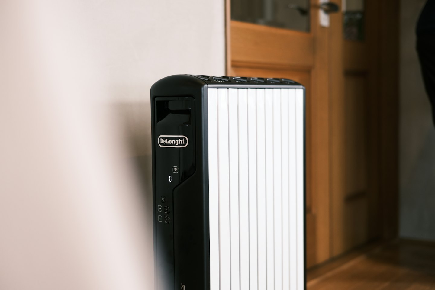 Black and white electric heater standing against a beige wall.