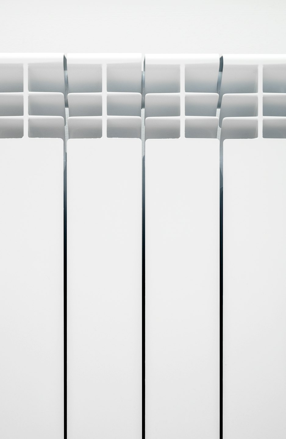 Modern white radiator with vertical fins and horizontal channels.